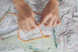 Hands working to place yarn along routes on a map