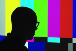 Silhouette of male in front of the Emergency Broadcast System colored bars