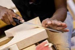 A Furniture Design student hand-filing a block of wood