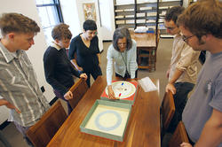 students around a table looking at a piece of art