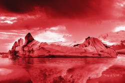 a red-filtered image of an iceberg floating on water, with a dark sky overhead