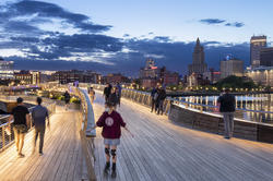 people walk at night across bridge near RISD campus with Providence skyline behind them