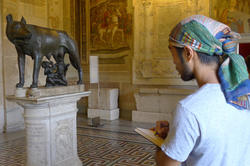 A student sketches a bronze statue while in a museum