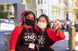 two masked students pose arm in arm for the camera