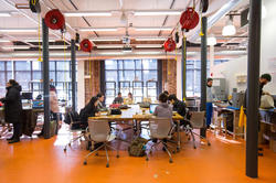 RISD students sitting at a long conference table or at workstations inside the Co-Works Research Lab