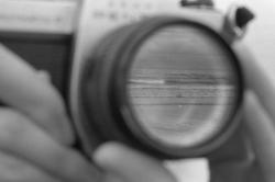 a black-and-white photo by RISD alum John Shen of hands focusing a camera lens