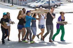 a group of RISD Pre-College students walking outdoors, with several carrying a large architectural model