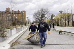 Two Alumni volunteers carrying leaves at a cleanup event