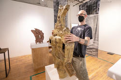 grad student Jacob Sussman sets sculpture on a pedestal