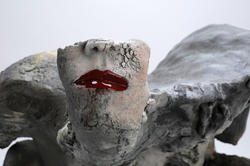 closeup of a ceramic statue of a winged person wearing red lipstick, head cut off from the nose up