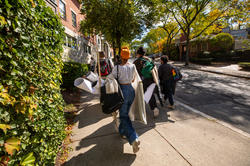 a group of students holding their work are walking up the hill alongside the freshman quad on a sunny day