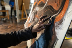 Close up of a first year EFS student putting the finishing touches on their charcoal drawing