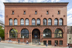 students walking on the sidewalk in front of the red brick Waterman Building on RISD’s campus