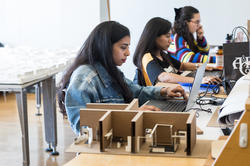 Three students at computers in interior architecture studio.