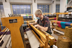 Student weaving in textiles studio.