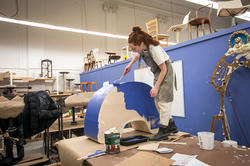 furniture design student paints a blue object in the upholstery studio