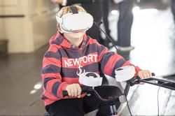 a kid wearing a VR headset rides a stationary bicycle