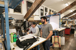 Two arch students laughing in studio in front of computer.