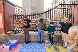 textiles students lead an interactive weaving workshop on the providence canal bridge using various colors of chunky fabrics