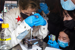 Students gather around a lab and conduct an experiment on biomaterials