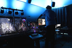 student working on a synthesizer in a darkened sound studio