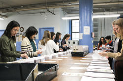 Members of the Alumni Club of Boston assemble copies of a Braille book at National Braille Press