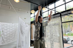 Corey Wantanabe string up clotheslines and hangs sheer lace fabric from them in the CIT building as a part of an installation for Snowtown monuments