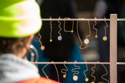 Image of a person in a green knit beanie cap looking at a display of glass bead earrings