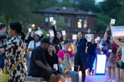 Image of people on a pedestrian bridge holding paper lanterns in the evening