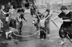 black-and-white image of kids playing in the spray from a fire hydrant
