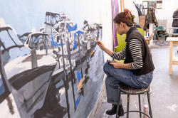 a student working on a huge painting in studio
