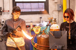 Lu Heintz helps a student adjust the flame on a blowtorch