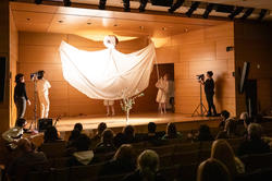 A massive white dove spreads its wings across the Metcalf Auditorium stage