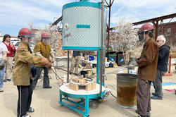 Students in protective gear prepare to remove fired ceramics pieces from the new raku kiln