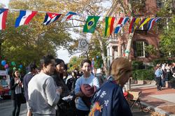 A group of international students eat and drink under a banner of international flags. 