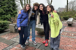 four happy POD grads pose for a photo in front of Woods-Gerry House
