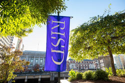 the sun illuminating a RISD flag on a summer day