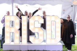 visiting alums pose with giant RISD lights