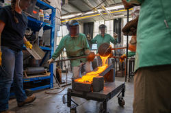 Student pour molten glass onto slanted blocks
