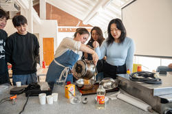 A group of students and a professor pour caramel into a steel bowl