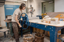 a student uses a hand-powered roller to flatten a slab of clay for the ram press