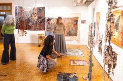 Mary Anne Friel and other faculty members consider a room of final student textiles