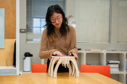 student presents a small plywood-and-acrylic stool