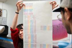 tech Nat Luo holds up a sample of digitally printed fabric in the Mimaki print room