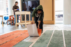 a student lays out long strips of painted paper on the floor