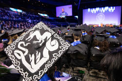 mortaboard decorated with image of dragon and RISD Commencement behind
