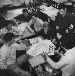 students looking at print collateral black and white historical photo