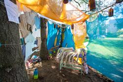 Outdoor space enclose by hanging colorful fabric between trees