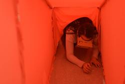 Student with virtual reality headset crawling through a red tunnel
