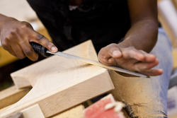 A Furniture Design student hand-filing a block of wood
